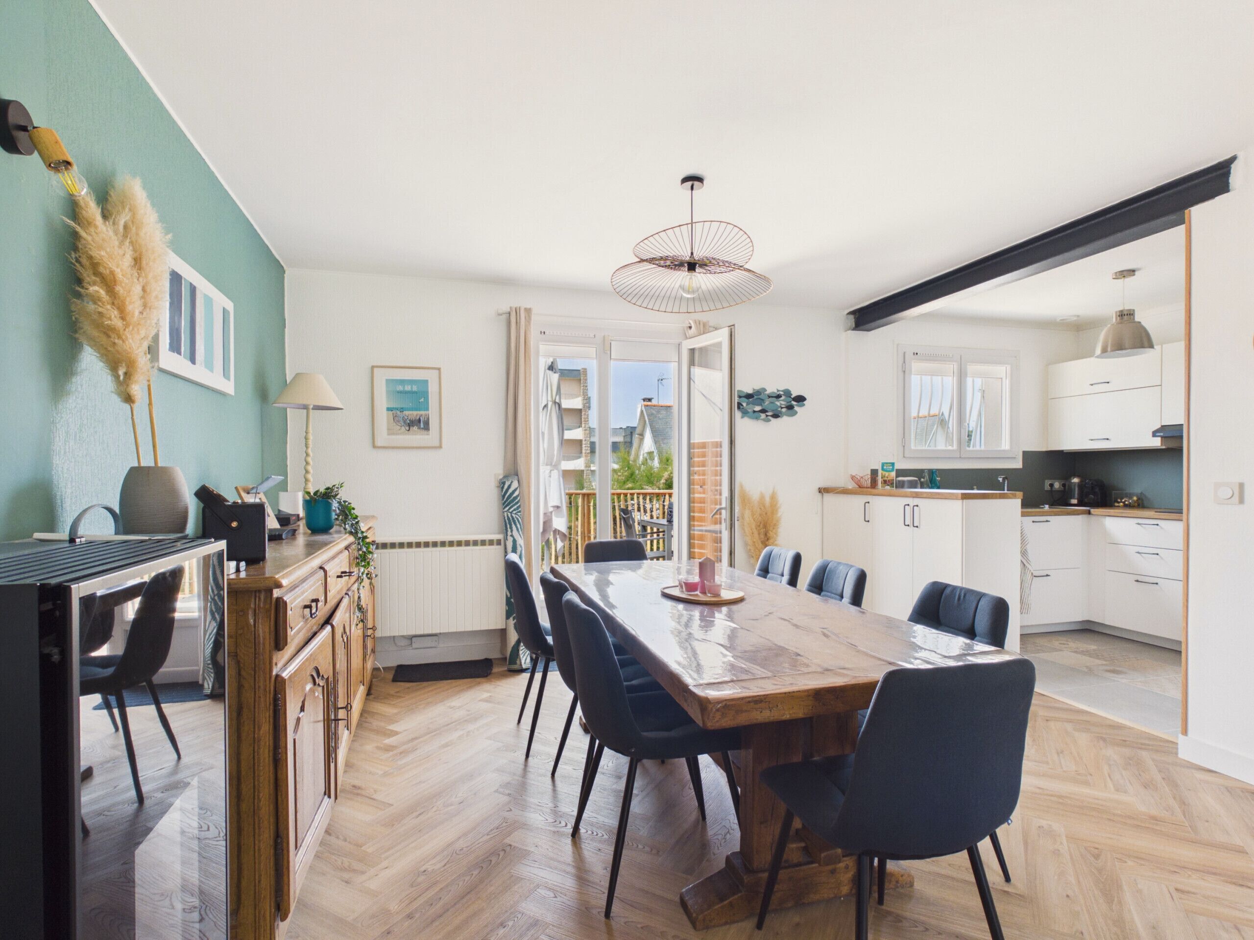A modern kitchen with white cabinets, a wooden dining table, and chairs.