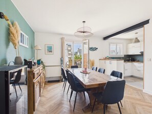 A modern kitchen with white cabinets, a wooden dining table, and chairs. - Near beach, house for 10 with garden (Erquy)