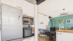 Eine moderne Küche mit Einbauofen, Mikrowelle und Kühlschrank. Es gibt einen Essbereich mit einem Holztisch und Stühlen.