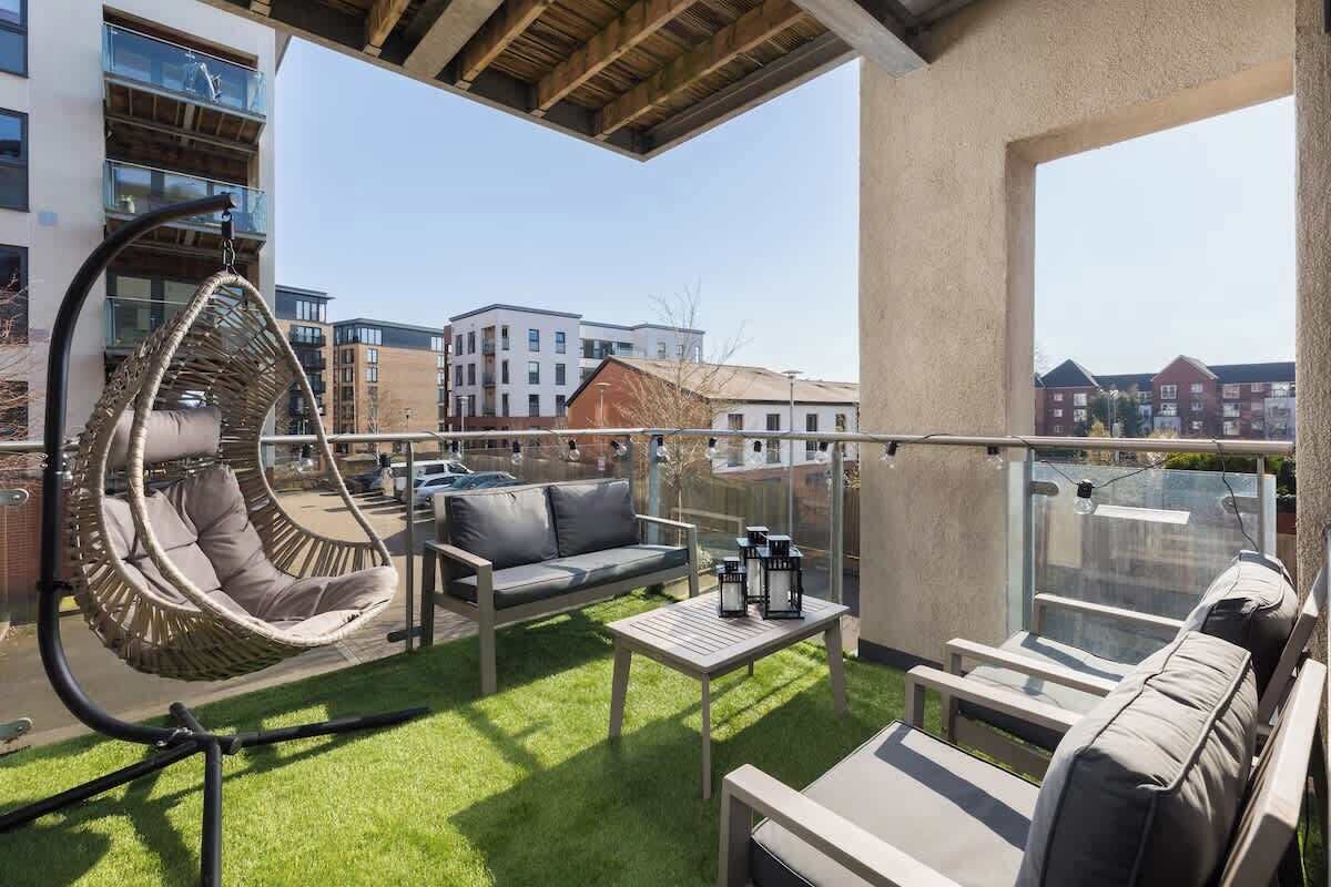 A balcony with a hanging chair, a sofa, a table, and a lounge chair.