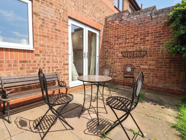 A patio with a bench, a table, and two chairs.