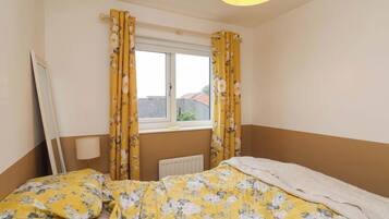 A bedroom with a bed, a radiator, and a window with curtains.