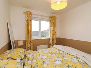 A bedroom with a bed, a radiator, and a window with curtains. - 7 Crestbrooke (Northallerton)