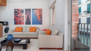 Una sala de estar con sofá, mesa de centro y una obra de arte en la pared.