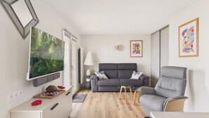 Un espacio habitable compacto con un sofá, una silla, un televisor y una pequeña mesa.