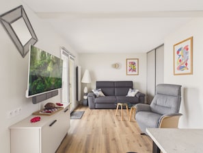 A compact living space with a sofa, a chair, a TV, and a small table. - Sea-view balcony & beach access - Sleeps 4 (Saint-Hilaire-de-Riez)