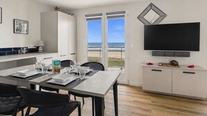Una cocina moderna con comedor, televisor y vista a la playa.