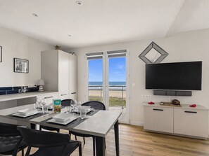 A modern kitchen with a dining area, a TV, and a view of the beach. - Sea-view balcony & beach access - Sleeps 4 (Saint-Hilaire-de-Riez)