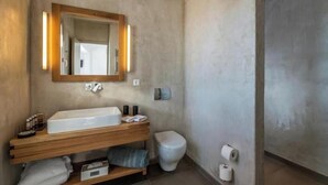 A bathroom with a wooden vanity, a mirror with lights, a toilet, and a shower area. - O Lofos TINOS Suite in Agios Stefanos with sea view (Mykonos)