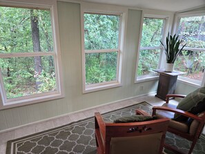 A room with large windows, a wooden chair, a rug, and a potted plant. - Trail-adjacent home with fenced yard. Pets Allowed! 
New A/C and heat. (Bella Vista)