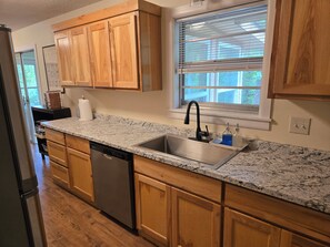 A kitchen with wooden cabinets, a granite countertop, a stainless steel sink, and a dishwasher. - Trail-adjacent home with fenced yard. Pets Allowed! 
New A/C and heat. (Bella Vista)