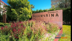 Schild für 'AQUAMARINA RESIDENCIAL' mit einem Garten im Vordergrund.