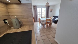Une cuisine moderne dotée d’un four à micro-ondes encastré, un coin repas avec une table et des chaises, et un salon avec un canapé.