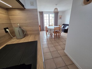 A modern kitchen with a built-in microwave, a dining area with a table and chairs, and a living room with a sofa. - Cozy cottage, garden, parking - 6 guests (La Tranche-sur-Mer)