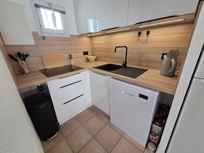 A modern kitchen with white cabinets, a black sink, and a dishwasher. - Cozy cottage, garden, parking - 6 guests (La Tranche-sur-Mer)