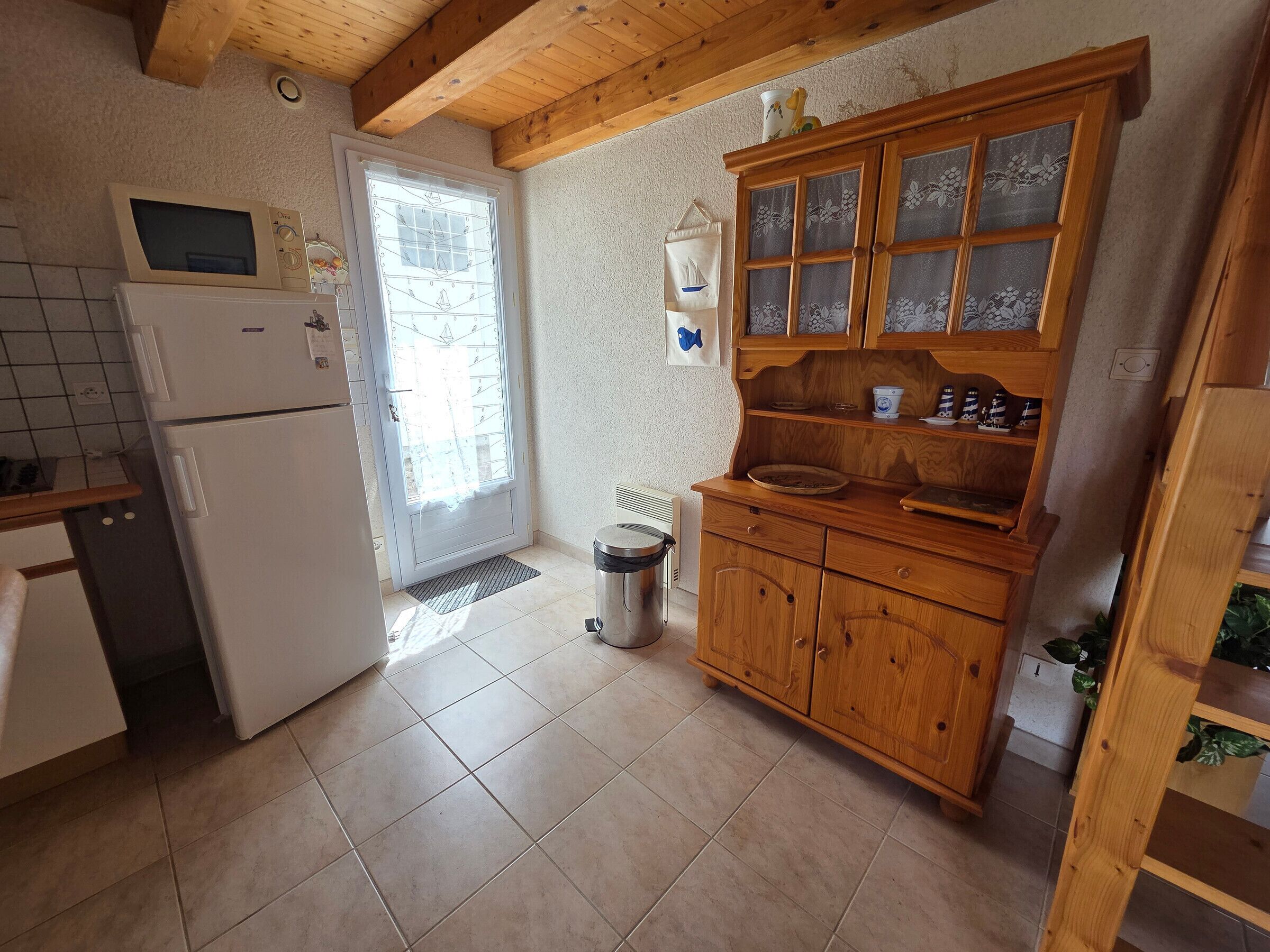 A kitchen with a refrigerator, oven, wooden cabinets, and a window with a view.