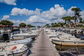 A marina with boats docked along a wooden walkway, trees, and buildings in the background. - Villa 'Micoco' with Private Terrace, Wi-Fi and Air Conditioning (Gujan-Mestras)