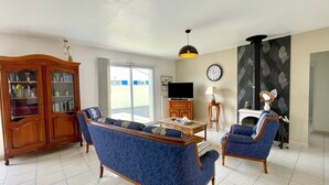 Ein Wohnzimmer mit einer Couch, Sesseln, einem Fernseher, einem Kamin und einem Bücherregal.