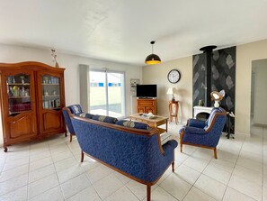 Ein Wohnzimmer mit einer Couch, Sesseln, einem Fernseher, einem Kamin und einem Bücherregal.