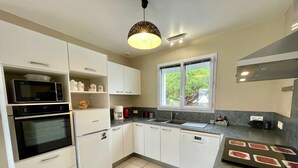 Eine moderne Küche mit weißen Schränken, einer Mikrowelle, einem Backofen und einer Kaffeemaschine.