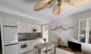 Eine moderne Küche mit weißen Schränken, einer Mikrowelle und einem Essbereich mit Tisch und Stühlen.