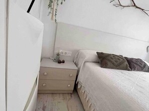 Ein Schlafzimmer mit einem Bett, einem Nachttisch und einer an der Wand befestigten Pflanze.