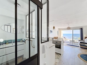 Eine moderne Küche mit Meerblick, ein Essbereich mit Ausblick und ein Wohnbereich mit Sofa und Tisch.