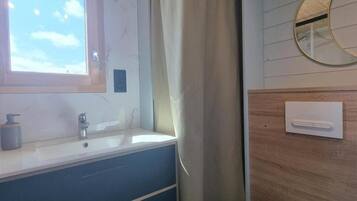 A bathroom with a window, a sink, a mirror, and a wooden panel wall.