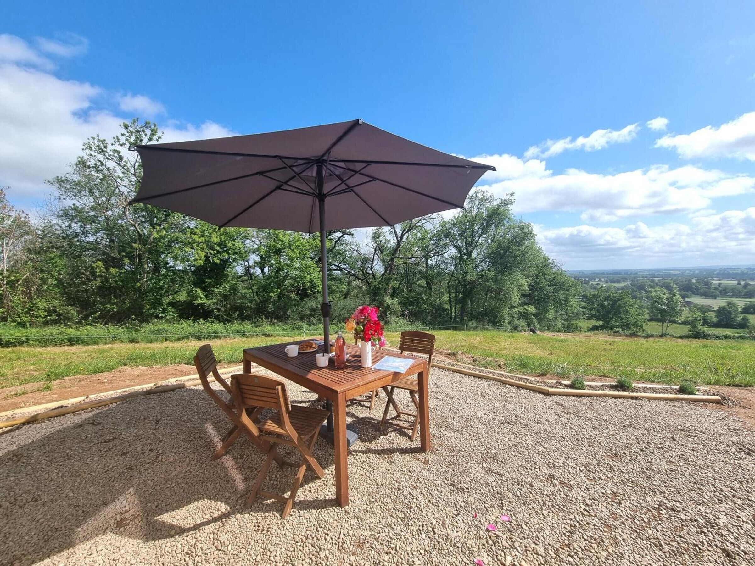An outdoor seating area with a table, chairs, and a large umbrella.