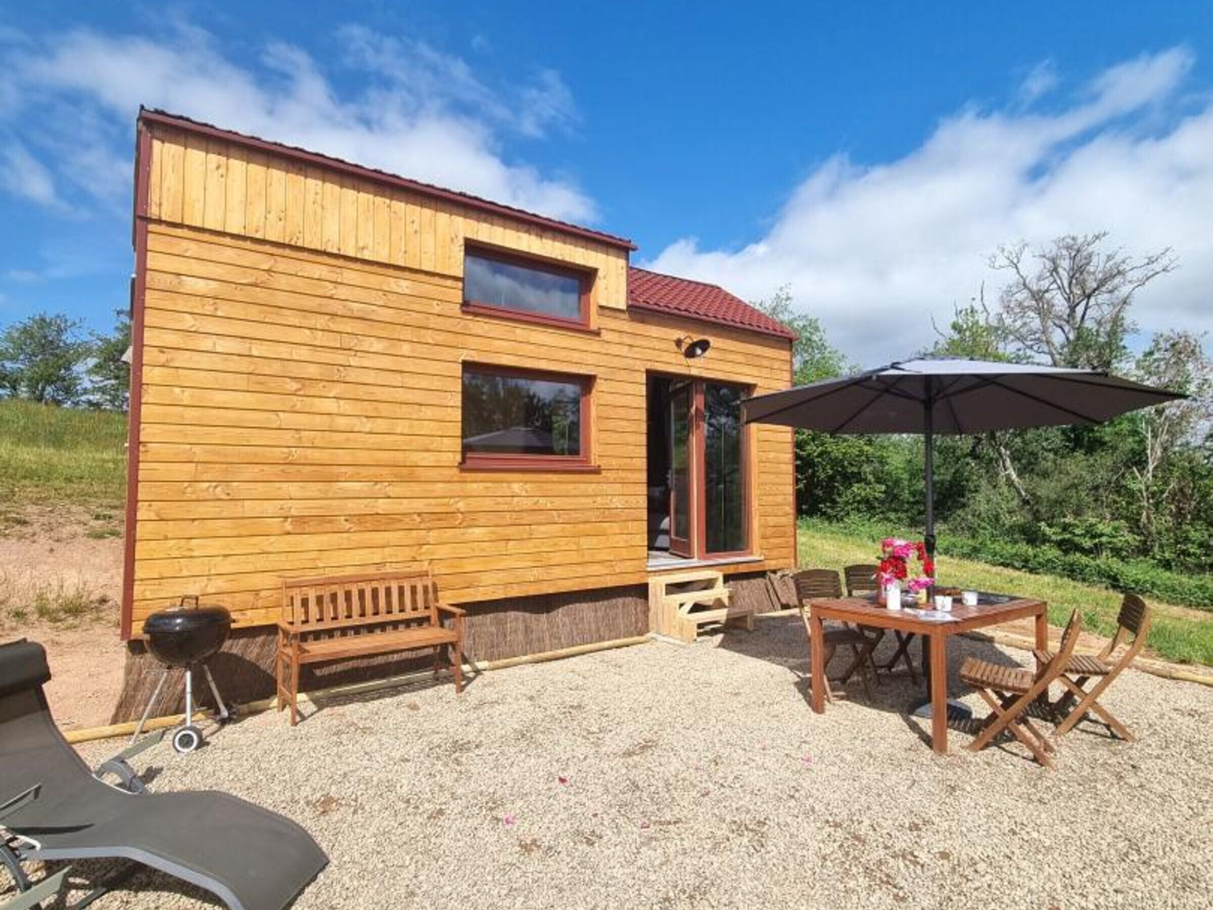 Une cabane en bois dotée d’un patio, d’un barbecue et de meubles pour se détendre à l’extérieur.