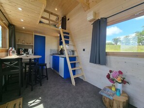 A cozy cabin interior with a kitchen, dining area, and a loft bedroom.