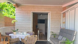 An outdoor patio with wicker furniture, a table set for dining, and a grey sofa. - House with private pool, parking, AC - 4 guests (Saint-Louis)