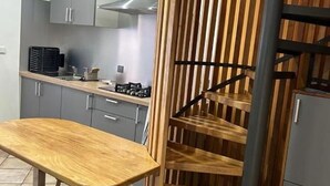 A modern kitchen with grey cabinets, a wooden table, and a staircase with a wooden railing. - House with private pool, parking, AC - 4 guests (Saint-Louis)