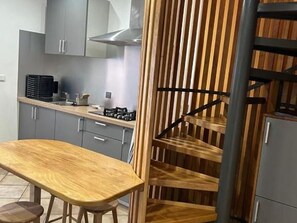 Eine moderne Küche mit grauen Schränken, einem Holztisch und einer Treppe mit Holzbalkon.