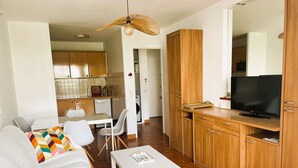 A modern living room with a sofa, a coffee table, and a TV on a wooden cabinet. - Air-conditioned apartment in city center - 2 guests (La Grande-Motte)