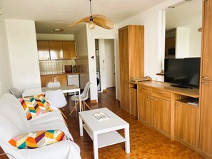 A modern living room with a sofa, a coffee table, and a TV on a wooden cabinet. - Air-conditioned apartment in city center - 2 guests (La Grande-Motte)