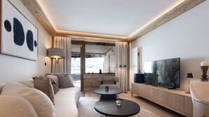 Ein modernes Wohnzimmer mit einer Couch, einem Couchtisch, einem Fernseher und Blick auf eine verschneite Landschaft.