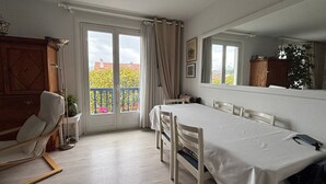 Una habitación con mesa de comedor, sillas, sofá, un espejo grande y un balcón con vistas.