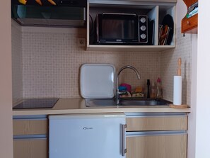 Eine kleine Küche mit Mikrowelle, Spüle und einem Kühlschrank.