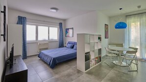 A bedroom with a bed, a desk, a chair, a bookshelf, and a dining area with a table and chairs. - The Yellow Roses: Family Room (Mandello del Lario)