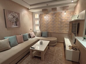 Ein modernes Wohnzimmer mit einem Ecksofa, einem Couchtisch und einer Wand mit Steinverkleidung.