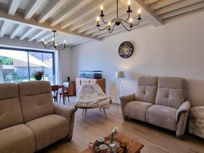 Ein Wohnzimmer mit zwei Sofas, einem Couchtisch, einer Kristallleuchter, einer Uhr und einem Fernseher.