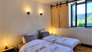 Un dormitorio con cama, lámparas de noche, una ventana con vistas y cabecera de madera.