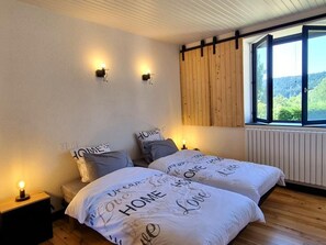 Ein Schlafzimmer mit Bett, Nachttischlampen, einem Fenster mit Blick und einem Holzkopfende.