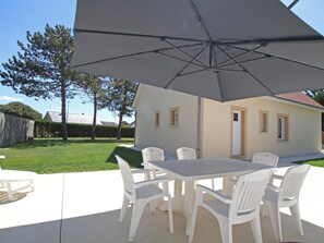 A patio with a table and chairs, a large umbrella, and a house in the background. - House near beach, pets welcome, parking - 6 guests (Bretteville-sur-Ay)