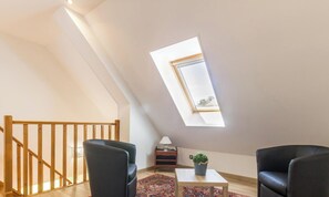 A room with a sloped ceiling, a skylight, a wooden staircase, two black chairs, a small table with a plant, and a lamp. - House near beach, pets welcome, parking - 6 guests (Bretteville-sur-Ay)