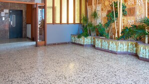 Un vestíbulo amplio con un muro estampado, una recepción y una puerta que da a otra zona.
