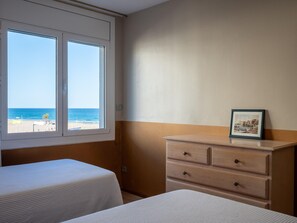 A hotel room with a bed, a dresser, and a window with a beach view. - Bright apartment, sea view - 6 guests (Torredembarra)