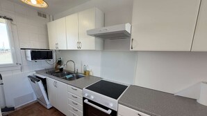 A compact kitchen with white cabinets, a microwave, a sink, and a stove. - Apartment with parking - 4/6 guests (Port Leucate)