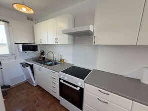Una cocina compacta con armarios blancos, un microondas, un lavabo y una estufa.